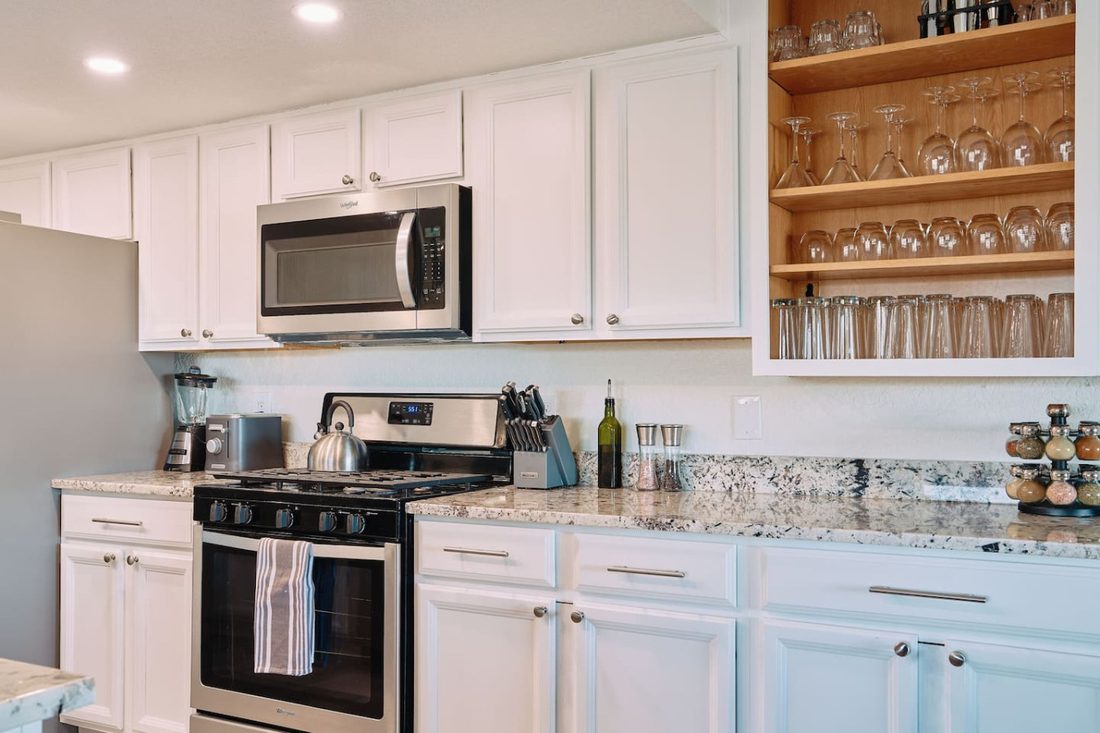Remodeled kitchen with granite counters, stainless appliances, and open glass shelving